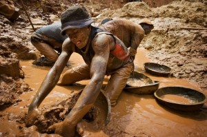 Gold miner scoops mud while digging an open pit in northeastern Congo